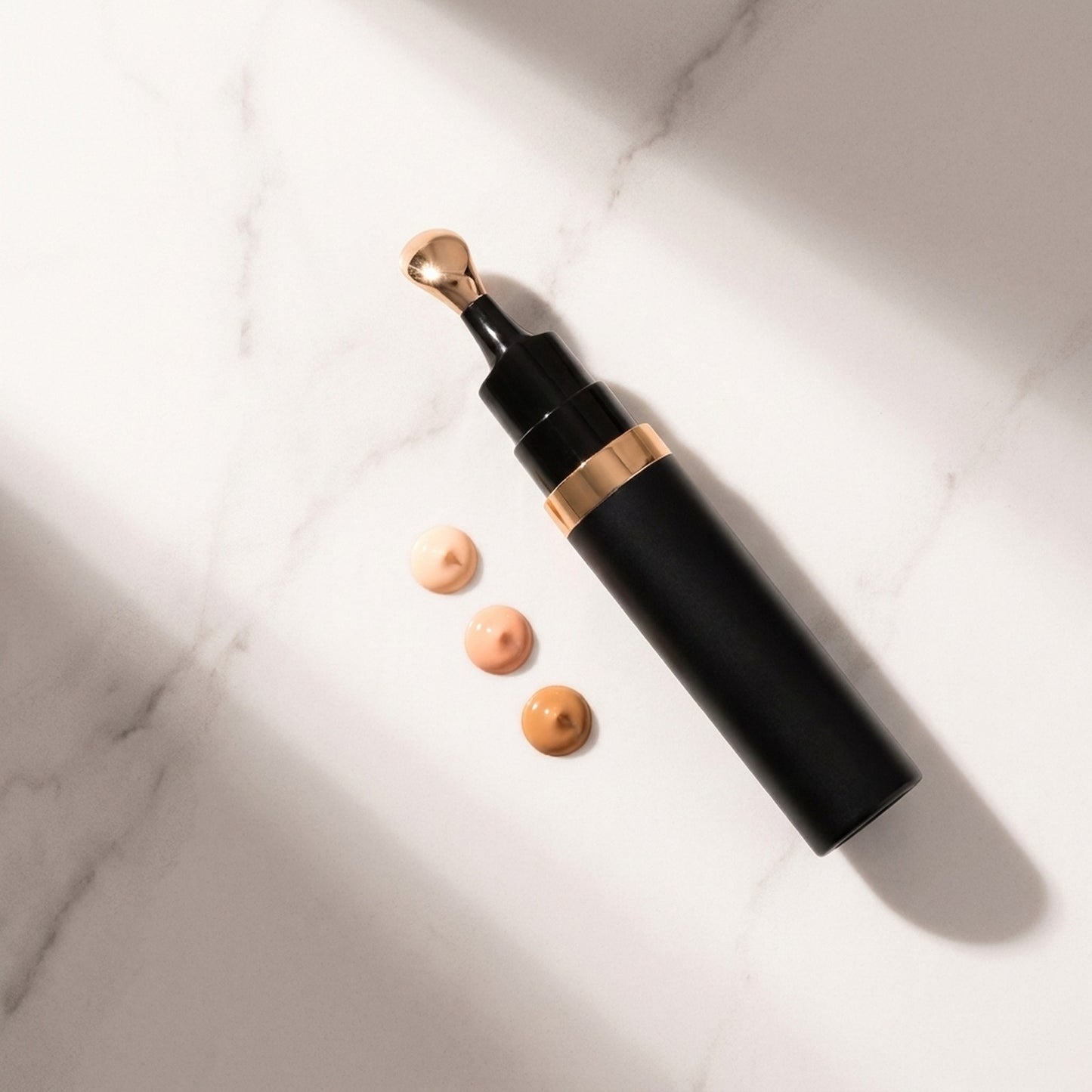 Corrector wand with three peach shades on marble